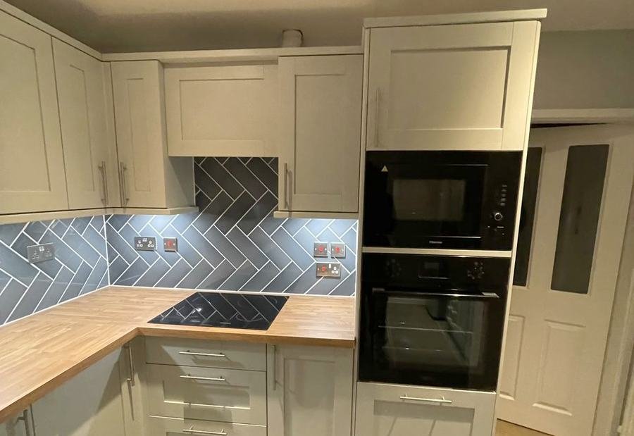 Cream shaker kitchen with a herringbone tiled splashback and oak worktop