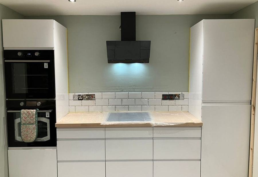 Finished white kitchen with an extractor, tiled splashback and oak worktop