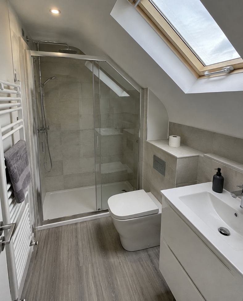Walk in shower with brass fittings, a lit niche and a wall hung vanity