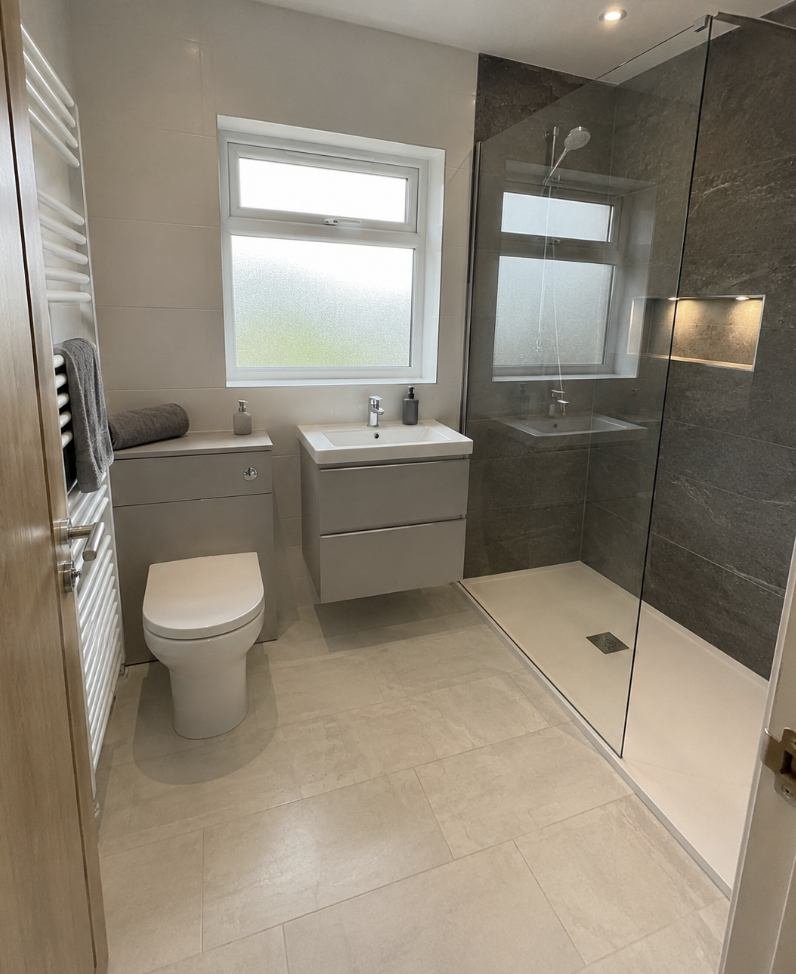 Walk in shower with a slate feature wall, lit niche and wall hung vanity