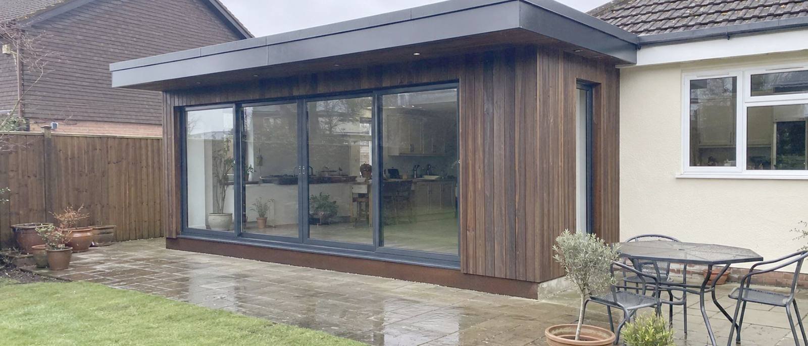 Timber clad garden room with sliding doors onto a patio