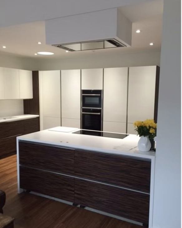 White gloss kitchen with a dark wood island and integrated extractor