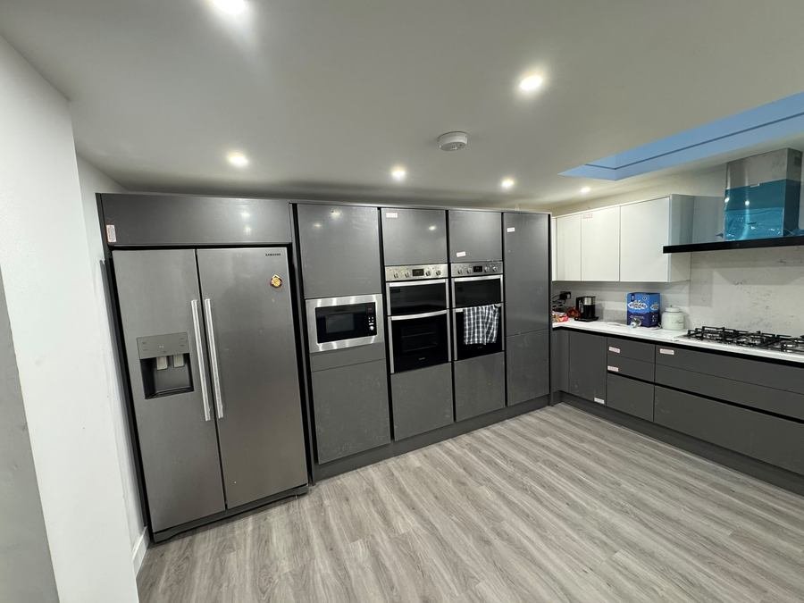 Grey handleless kitchen with integrated ovens and an American fridge freezer