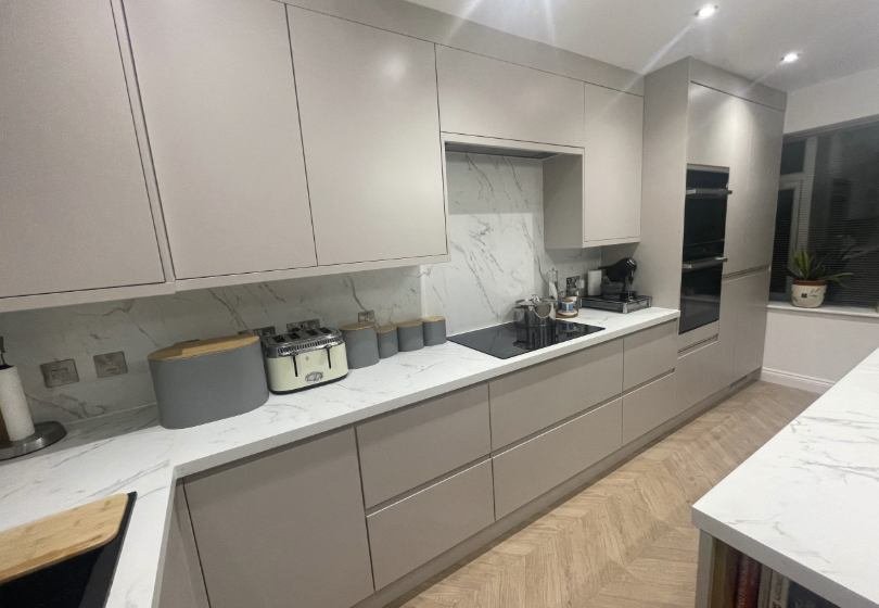 Handleless kitchen with a marble splashback and herringbone flooring