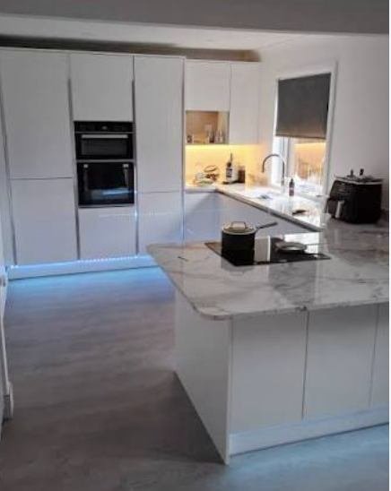 White gloss kitchen with a marble worktop and under unit lighting