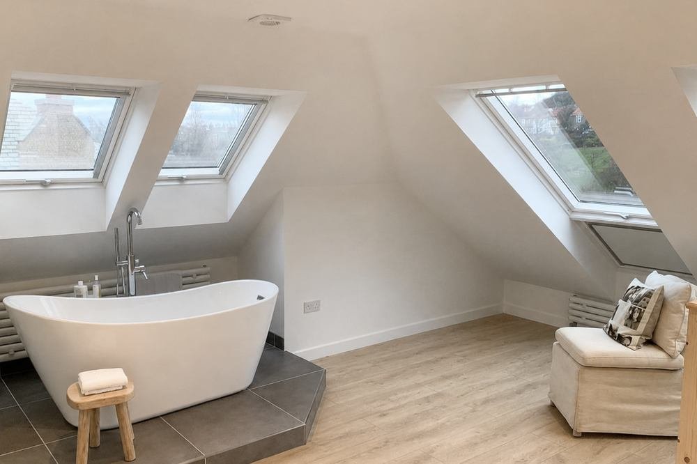 Loft bathroom with a freestanding bath set on a tiled plinth under the velux windows